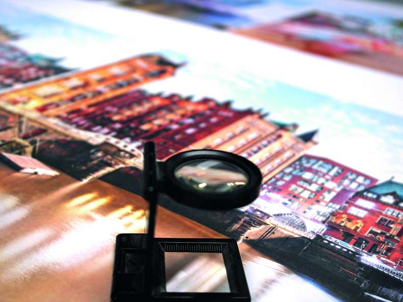 Vergrößerungsglas auf gedrucktes Druckerzeugnis mit Häuserfront - PSO-Druck