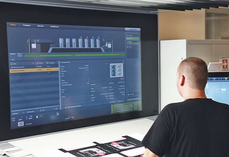 Großer Bildschirm von Offsetdruckmaschine, Mensch steht davor und bedient die Technik, Druckerei Hamburg